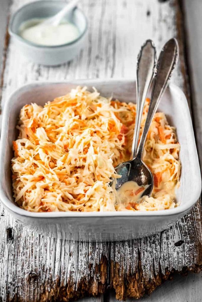 Eine Schüssel mit Coleslaw und Salatbesteck auf Holz