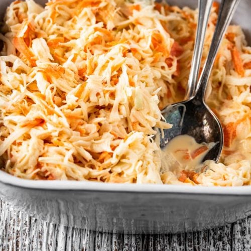 Eine Schüssel amerikanischer Krautsalat und Salatbesteck auf Holz