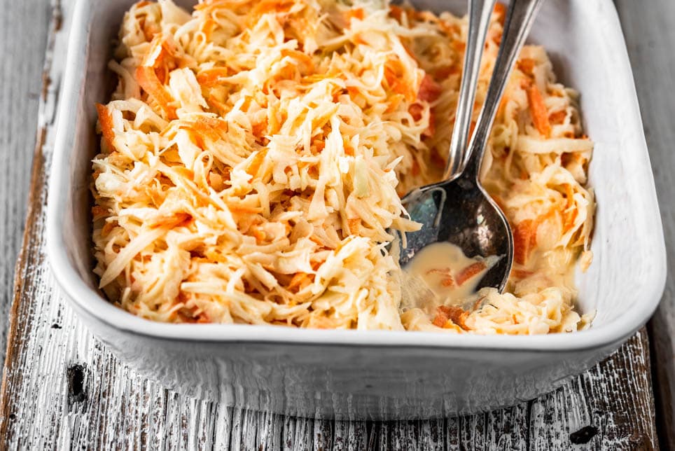 Eine Schüssel amerikanischer Krautsalat und Salatbesteck auf Holz