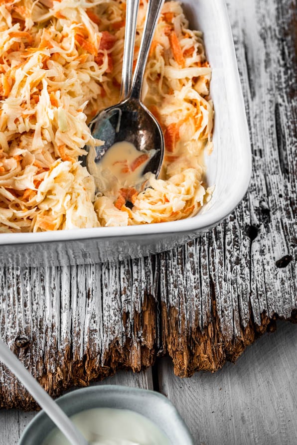 Eine Schüssel mit Coleslaw und Salatbesteck auf Holz