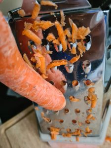 Eine Karotte wird auf Vierkantreibe geraspelt