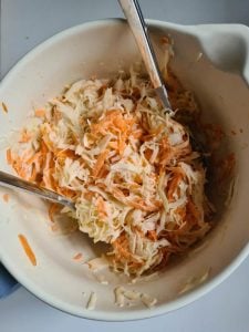 Coleslaw wird in einer Schüssel mit 2 Löffeln gemischt