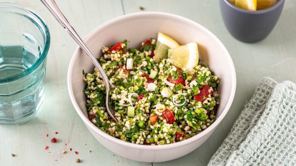 Zwei Schüsseln mit Tabouleh und Gläsern auf Tisch