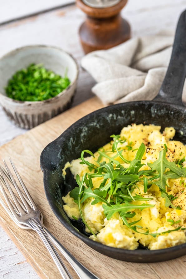 Ein Pfännchen Rührei Rezept klassisch mit Schnittlauch auf einem Brett.