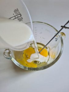 Milch wird mit Eidottern in einem Glasmessbecher gemischt