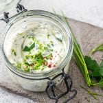 Ein Einmachglas mit Kräuterquark und gehackten Kräutern