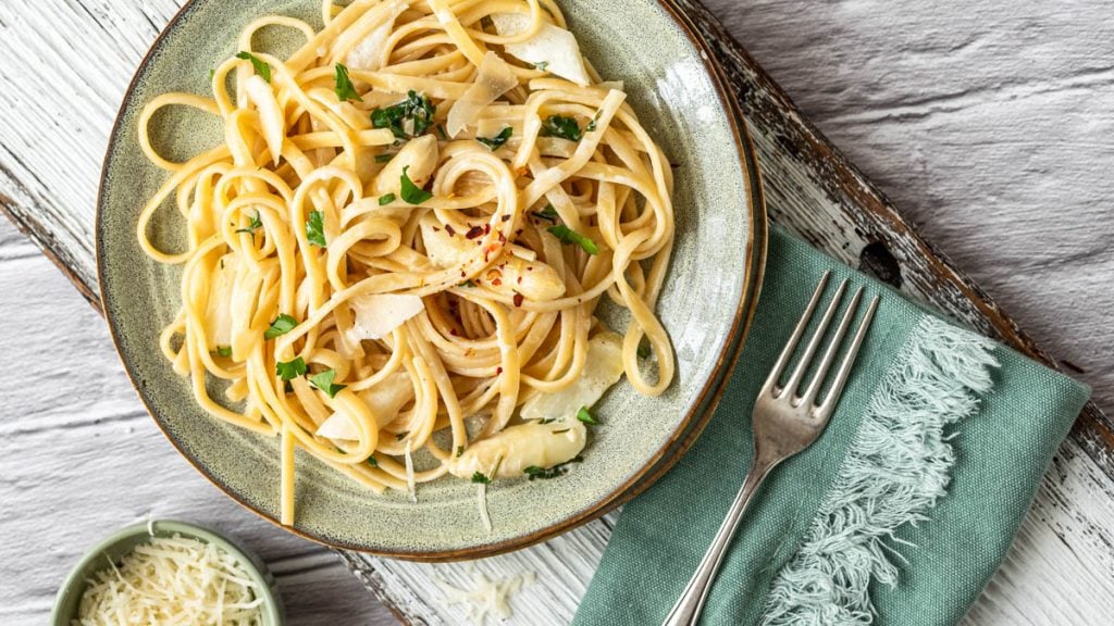 Pastateller mit Pasta al limone mit Spargel und Schälchen mit Parmesan