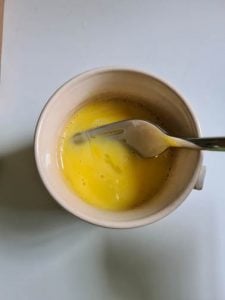 Ei wird in Tasse verquirlt