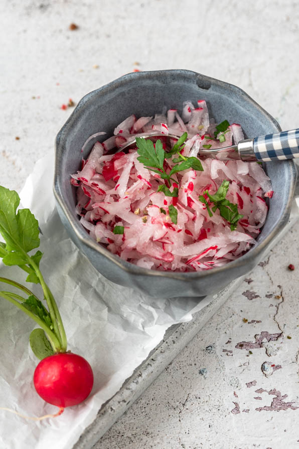 Salat mit Radieschen in Schüsselchen auf Tablett
