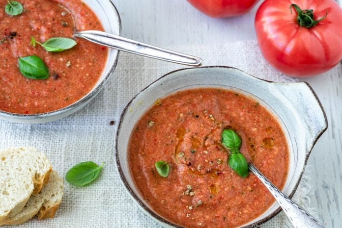 Zwei Schalen mit Gazpacho andaluz mit Baguettescheiben und Tomaten