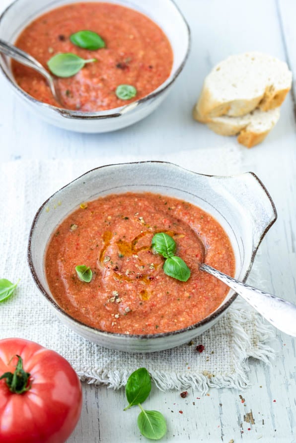 Zwei Schalen mit Gazpacho andaluz mit Baguettescheiben und Tomaten