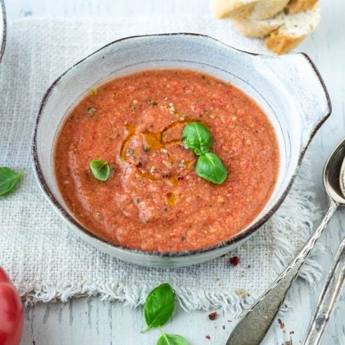 Zwei Schalen mit Gazpacho andaluz mit Baguettescheiben und Tomaten