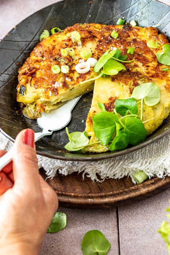 Angeschnittene spanische Tortilla in Pfanne mit Kräutern