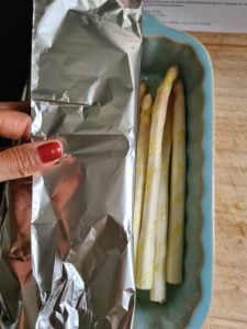 Spargel in Auflaufform wird mit Alufolie abgedeckt