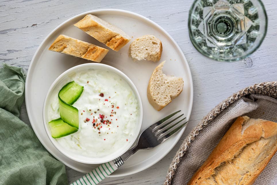 Tzatziki mit Baguette und einem Glas Wein am Tisch