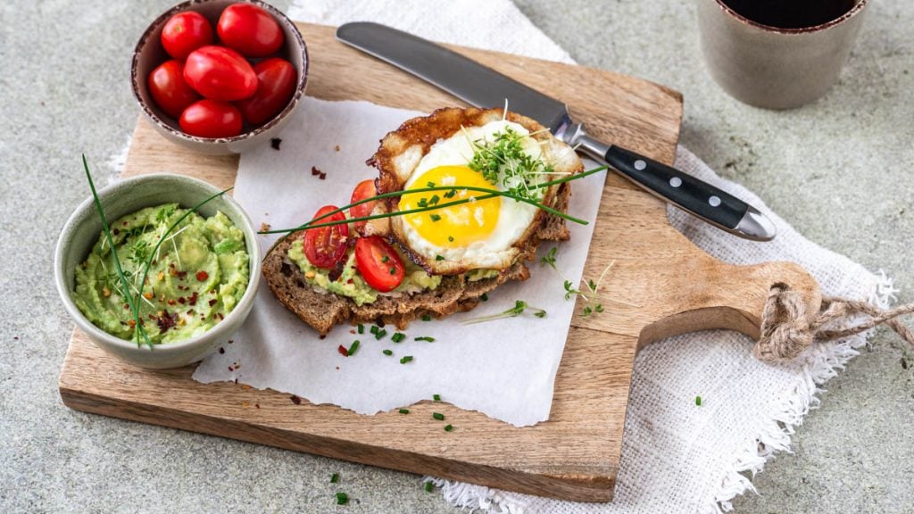 Strammer Max vegetarisch mit Avocado und Tomaten auf Holzbrettchen