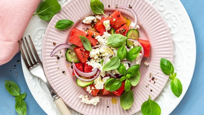 Wassermelonen Feta Salat auf Tellern angerichtet und mit Basilikum garniert