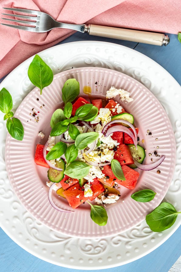 Wassermelonen Feta Salat auf Tellern angerichtet und mit Basilikum garniert