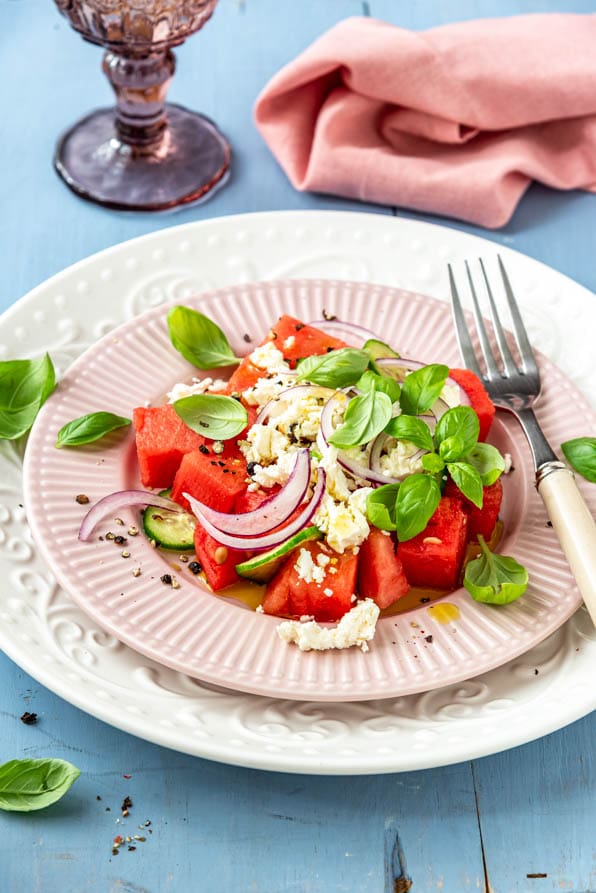 Wassermelonen Feta Salat auf Tellern angerichtet und mit Basilikum garniert