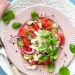 Wassermelonensalat mit Feta auf Tellern angerichtet und mit Basilikum garniert