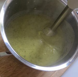 Zucchinisuppe wird mit einem Pürierstab gemixt