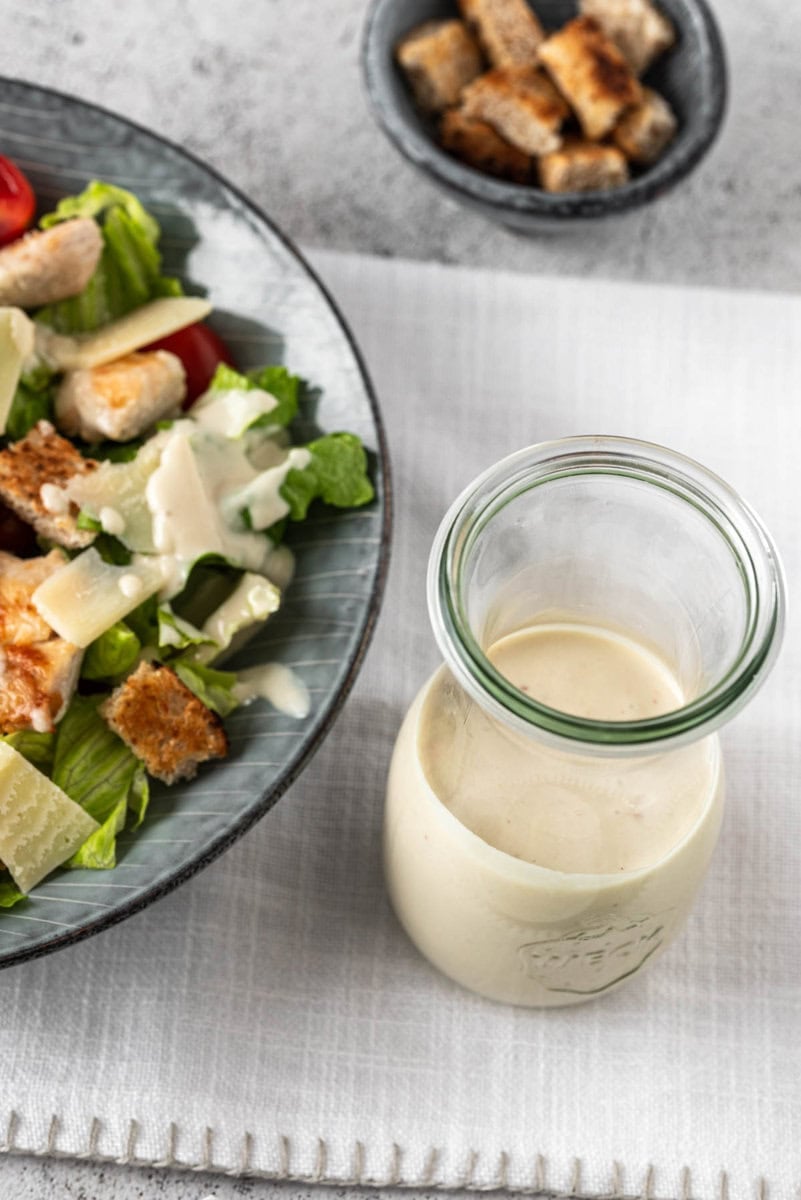 Caesar Dressing steht neben Caesar Salat mit Croutons