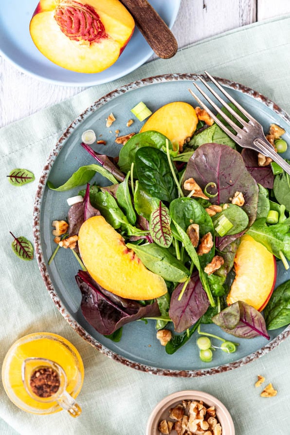 Sommersalat mit Nektarinen auf einem Teller und eine aufgeschnittene Nektarine daneben - Mundgefühl Foodblog