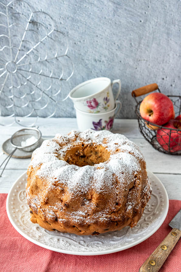 Ganzer Apfel Gugelhupf mit Tassen und Äpfeln auf Tisch - Mundgefühl