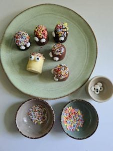 dekorierte Schaumküsse auf einem Teller. Daneben Streusel