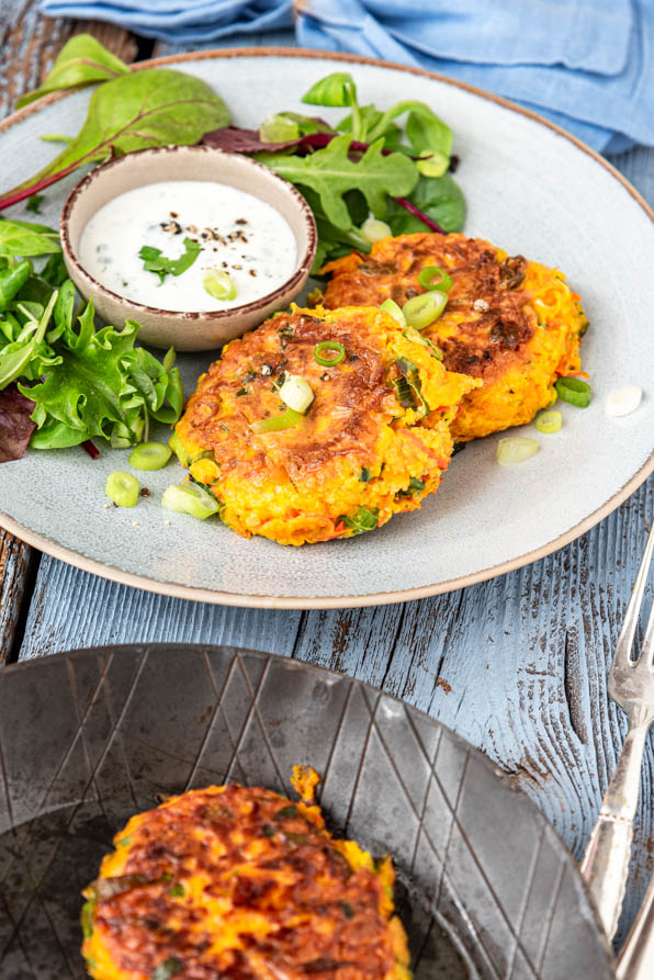 Gemüsepuffer mit Salat und Dip auf einem Teller. Daneben eine Pfanne - Foodblog Mundgefühl