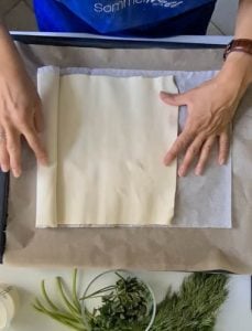 Blätterteig wird auf Backblech ausgerollt