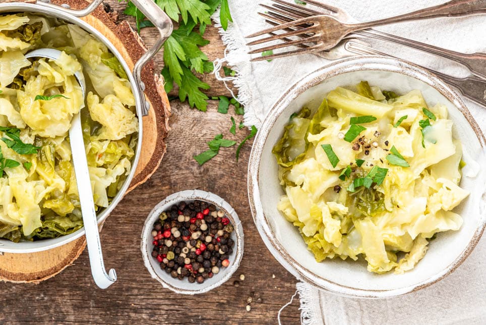 Eine Schüssel mit Wirsing und ein Topf daneben auf einem Tisch