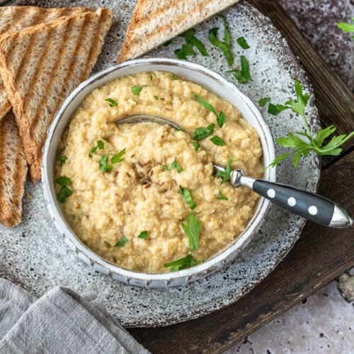 Eine Schale Hummus mit Toastbrot und einem Bund Petersilie