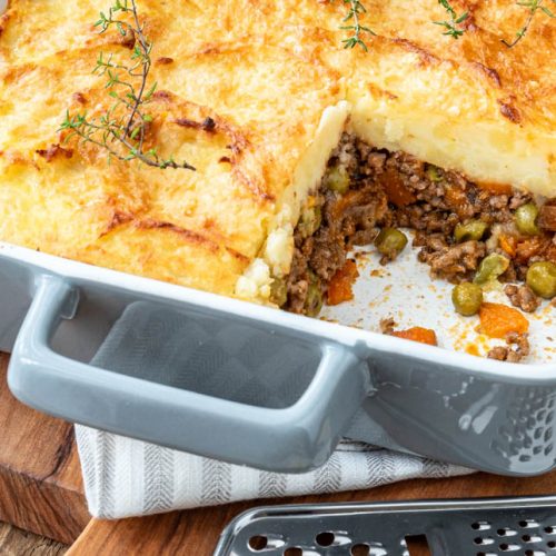 Shepherd's Pie in Auflaufform auf Holzbrett mit Käse