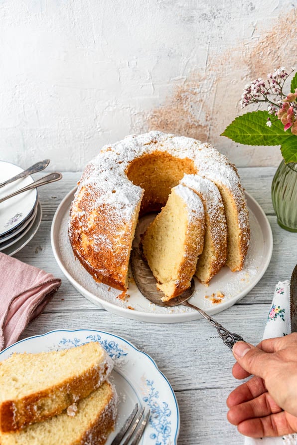 Angeschnittener Topfengugelhupf auf Tisch mit Blumen