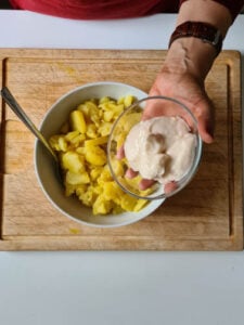 Mayo wird zu Kartoffelsalat gegeben.