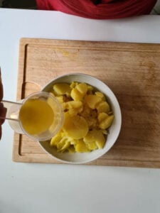 In Scheiben geschnittene Kartoffeln werden mit Brühe übergossen