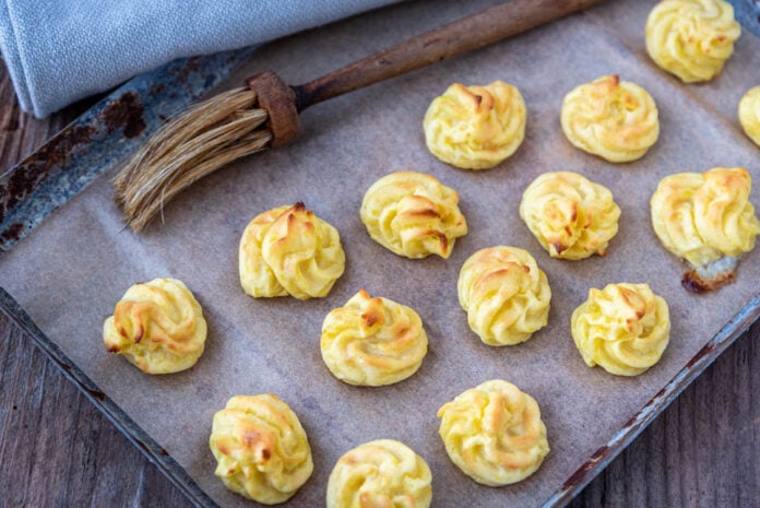 Herzoginkartoffeln auf Backblech mit Pinsel und Küchentuch