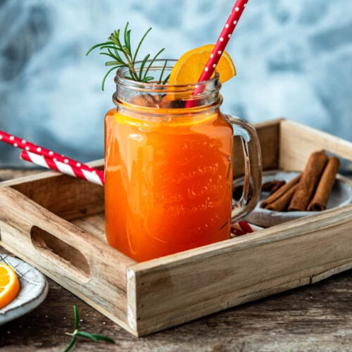 Ein Glas Hot Aperol mit Strohalm auf einem Tablett