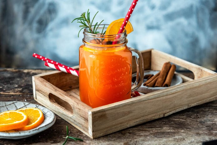 Hot Aperol Rezept: leuchtend orangefarbener Drink im Glas mit Rosmarinzweig und Zimt, stimmungsvoll serviert