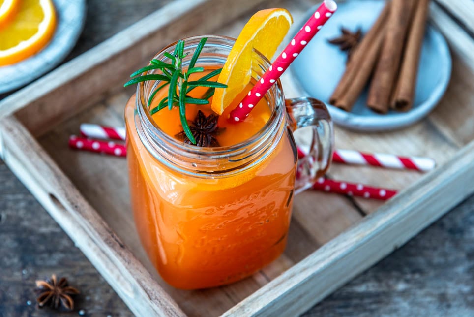 Hot Aperol mit Strohhalm und Zimtstangen auf Tablett