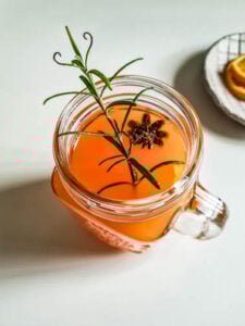 Mit Rosmarinzweig dekorierter Hot Aperol in Glas