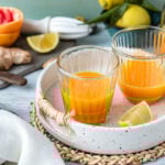 Zwei Gläser Ingwer Shot auf Tablett mit Grapefruits