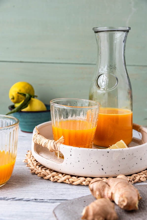 Eine Flasche Ingwer Shot mit einem Glas auf einem Tablett