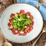 Klassisches Carpaccio auf Holzuntergrund mit Besteck