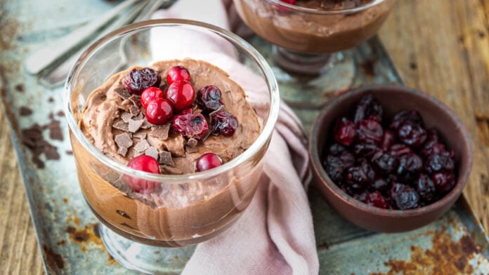 Mousse au chocolat mit Cranberries in 2 Gläsern auf Tablett