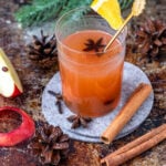 Ein Glas Punsch mit einer Apfelspalte und Zimtrinde