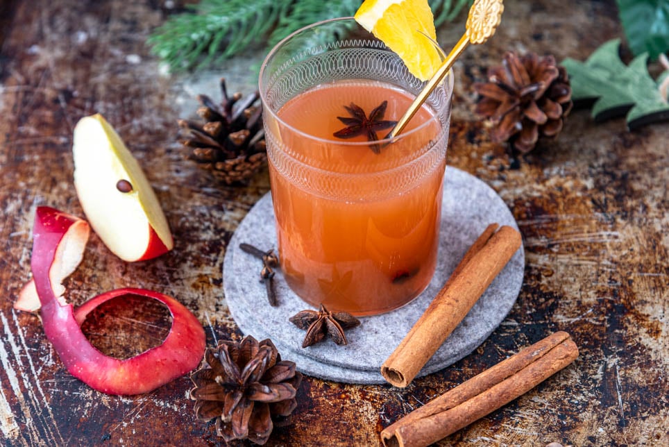 Ein Glas Punsch mit einer Apfelspalte und Zimtrinde