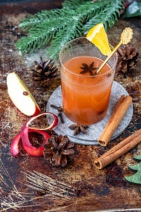 Ein Glas Punsch mit einer Apfelspalte und Zimtrinde