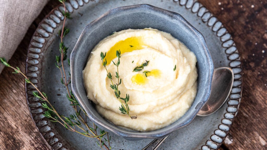 Ein Schüsselchen mit Selleriepüree mit Trüffelöl und einem Zweig Thymian